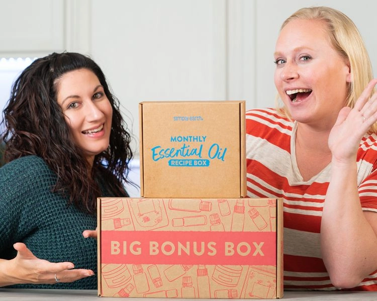 Two founders smiling beside a Monthly Essential Oil box and a Big Bonus Box