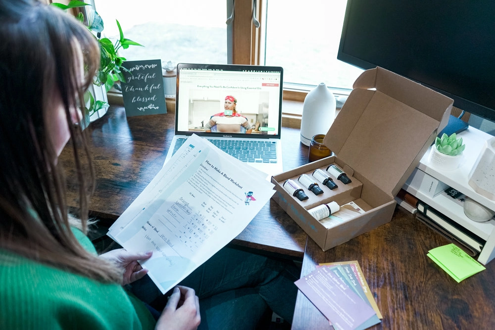 Course materials and a recipe box open on a desk beside a laptop